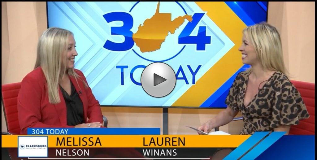 Two smiling adults on a TV set with a map and text on screen.